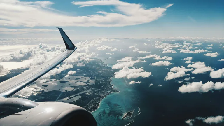 an airplane over a cloudy sky with water below