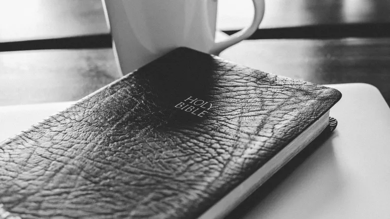 Bible and coffee mug on a table.