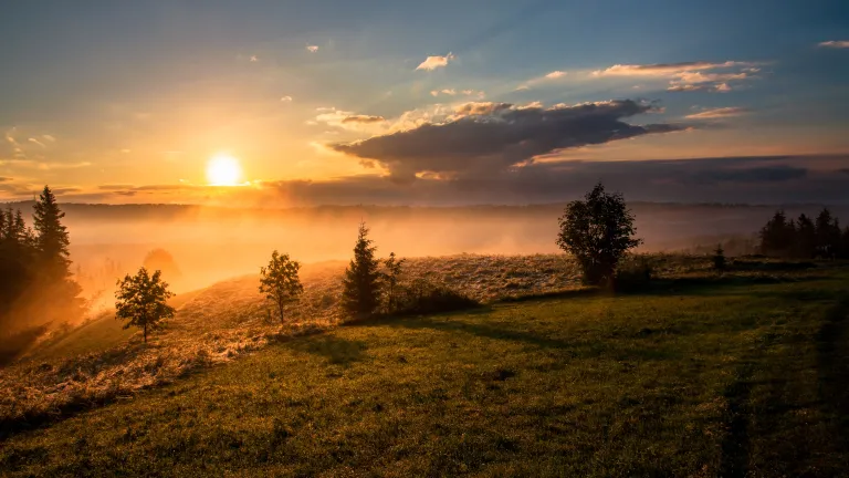 Photo of a sunset over the mountains with fog.