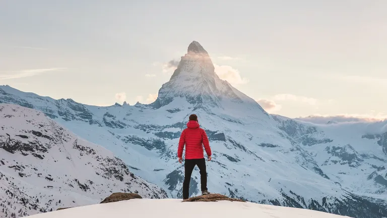 Photo of a man standing in front of a snowy mountain.