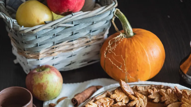 a basket of apples, pumpkin pie, coffee mug, and cinnamon stick