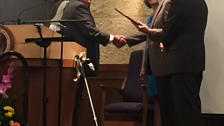 Randy Schreiber receiving the engraved plaque and shaking hands with Mike Miller.
