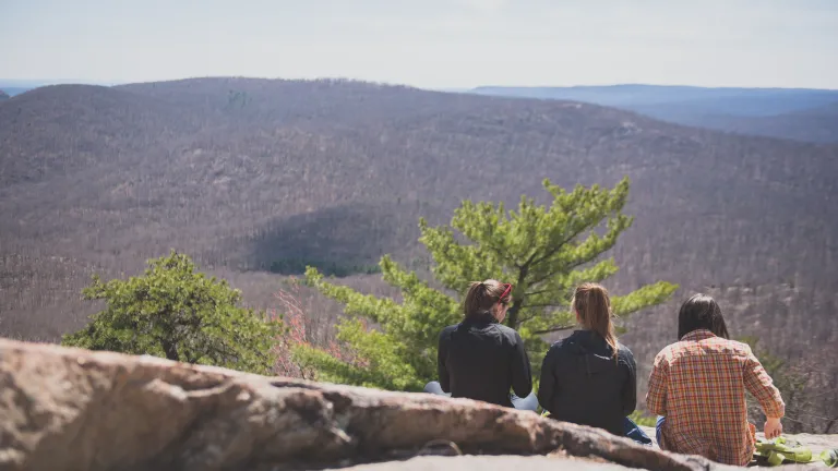 A photo of three friends gazing at the mountains, taken from behind.
