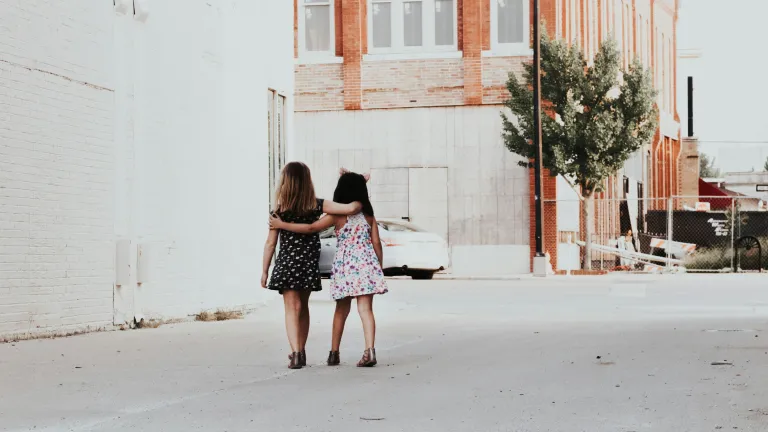 A photo of two young girls with arm around each other.