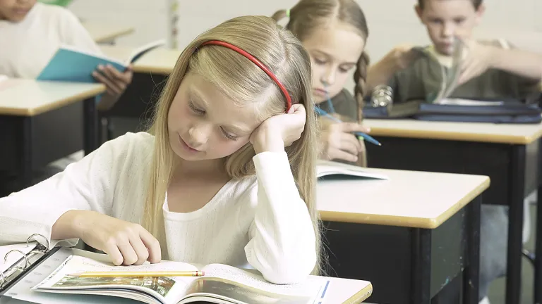 A girl looking at her school book.