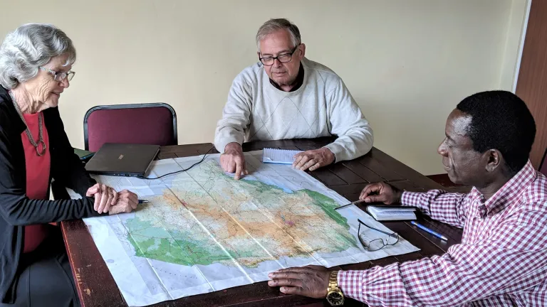 Mabasa Chichaya discusses the perils of Church members with Vic and Bev Kubik over a map of Zimbabwe.