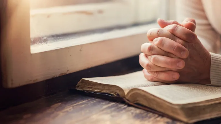 A woman praying with a Bible open.