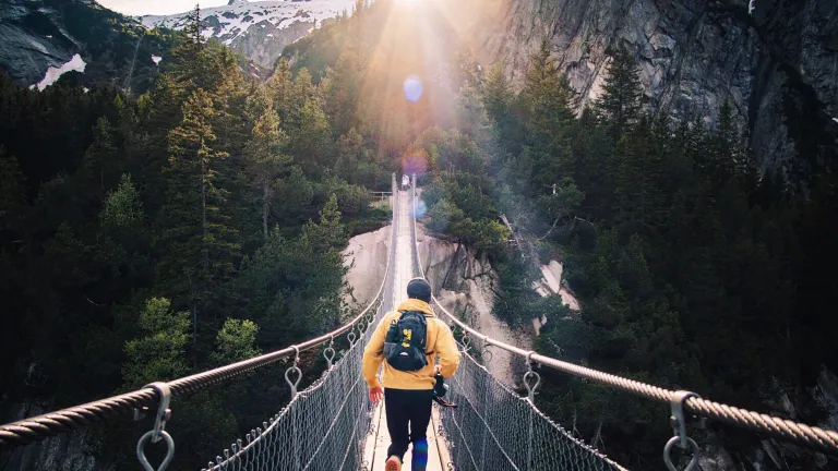 Man running across hanging bridge.