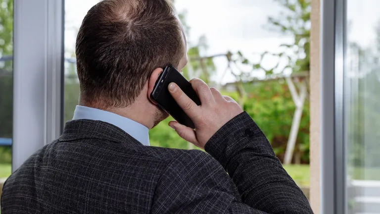 a man wearing a business suit talking on a cell phone and looking out a window