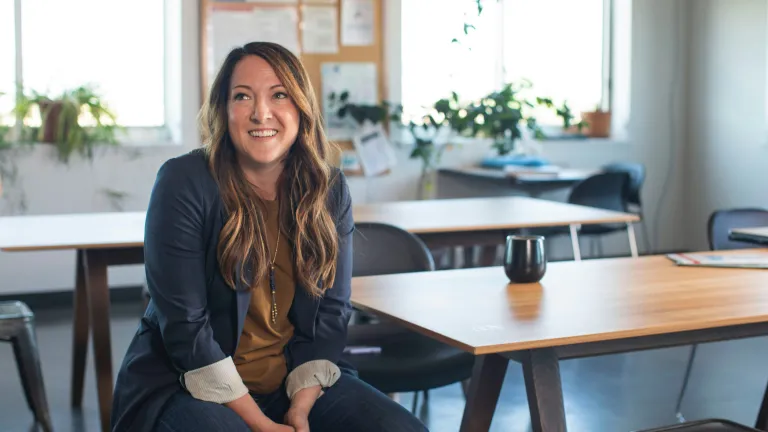 a smiling woman sitting in a chair next to a wooden table