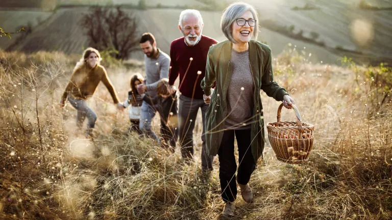A multi generation family walking in a field.