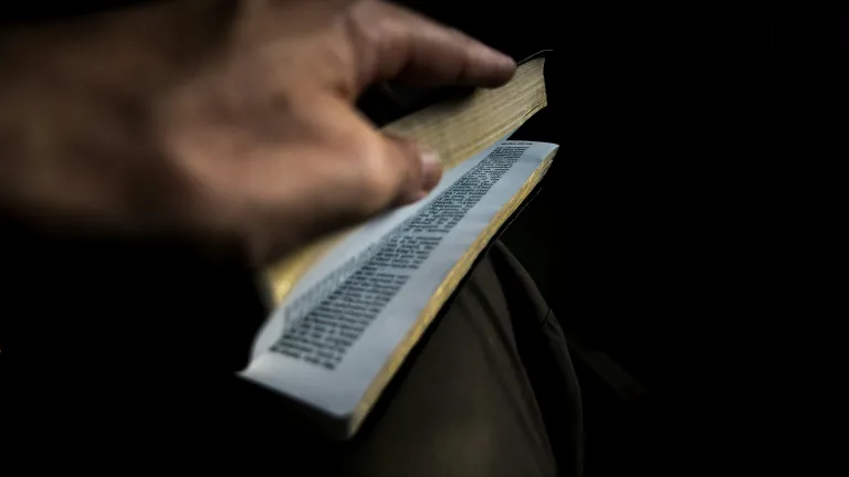 A close up of a hand flipping through pages of a Bible.