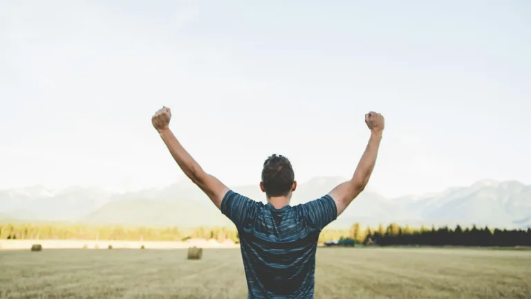 Man with arms in the air looking out at a field
