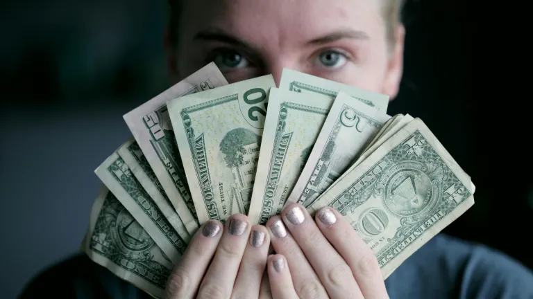 Woman holding money in front of face fanned out
