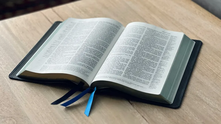 an open Bible on a light-colored wood table