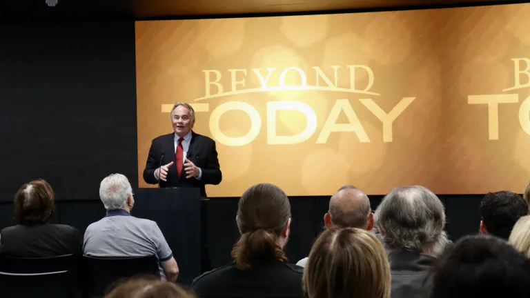 a man speaking to a crowd in front of a Beyond Today banner