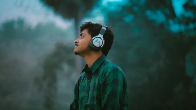 man in green and black plaid dress shirt wearing black and white headphones