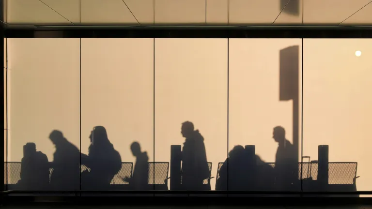 People walking creating shadows on building walls.