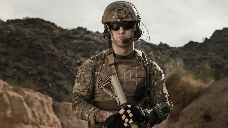 Would joining the military ever be appropriate for a follower of Christ? a soldier holding a weapon with a brown hilly terrain in the background