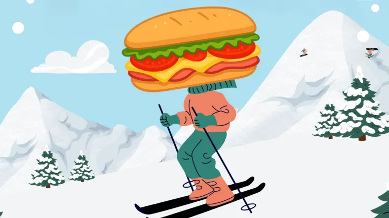 mountain slopes covered in snow with a skier front and center wearing a subway sandwich over their head