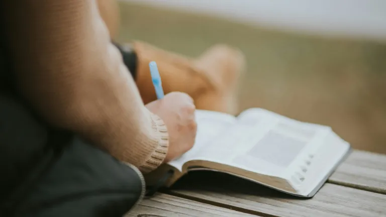 A woman taking notes inside of a Bible.