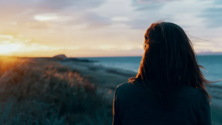 The hope of God’s Kingdom is not just a distant dream to passively wait for. It’s a powerful force that should be reshaping our lives today. A woman looking off in the distance with the sun setting.