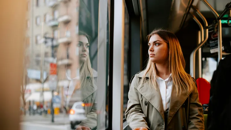 a woman on a bus looking out the window at a city