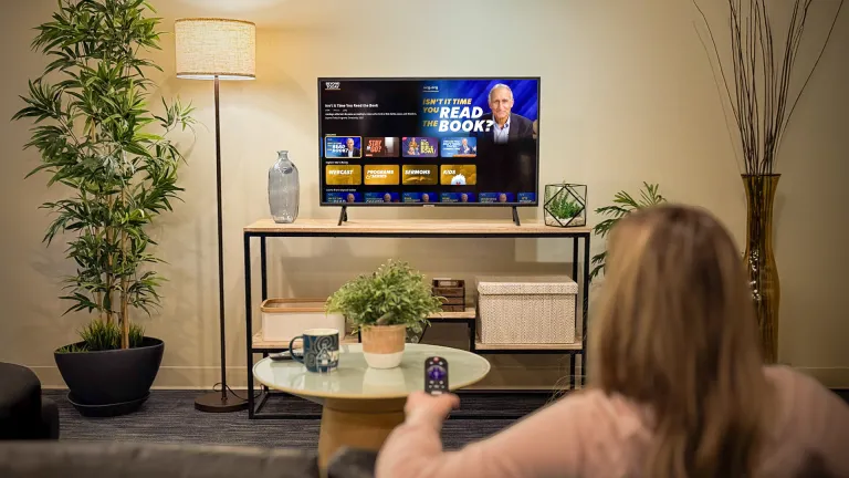a woman aiming a TV remote at a TV
