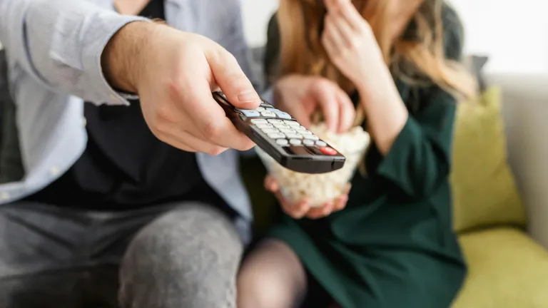 a man adn a woman seated on a sofa with a tv remote