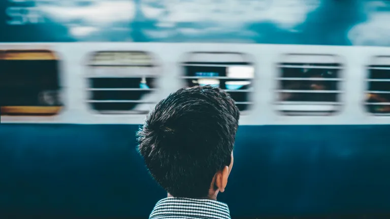 Young man facing away looking at a passing subway