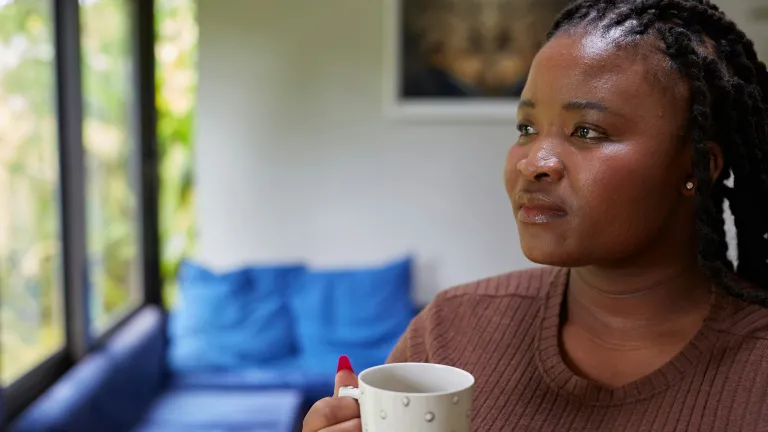 a woman holding a coffee mug and looking out the window