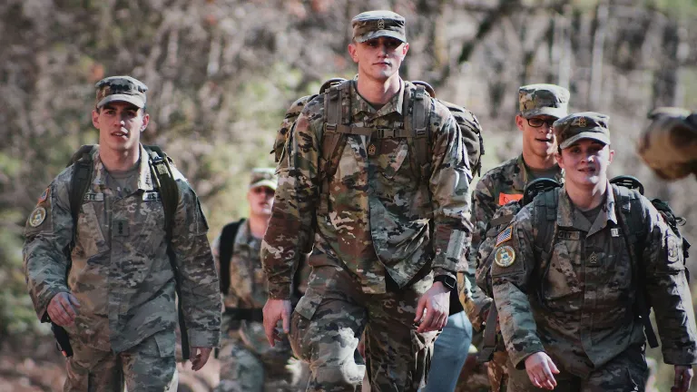 a group of young men wearing army camouflage uniforms and walking outdoors
