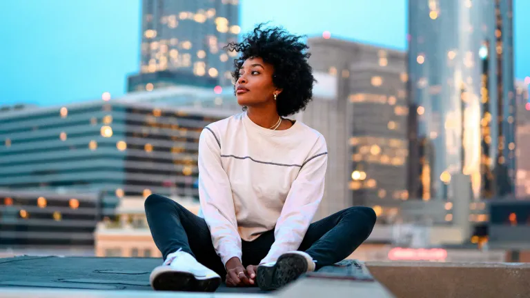 a woman sitting with high-rise city buildings in the background