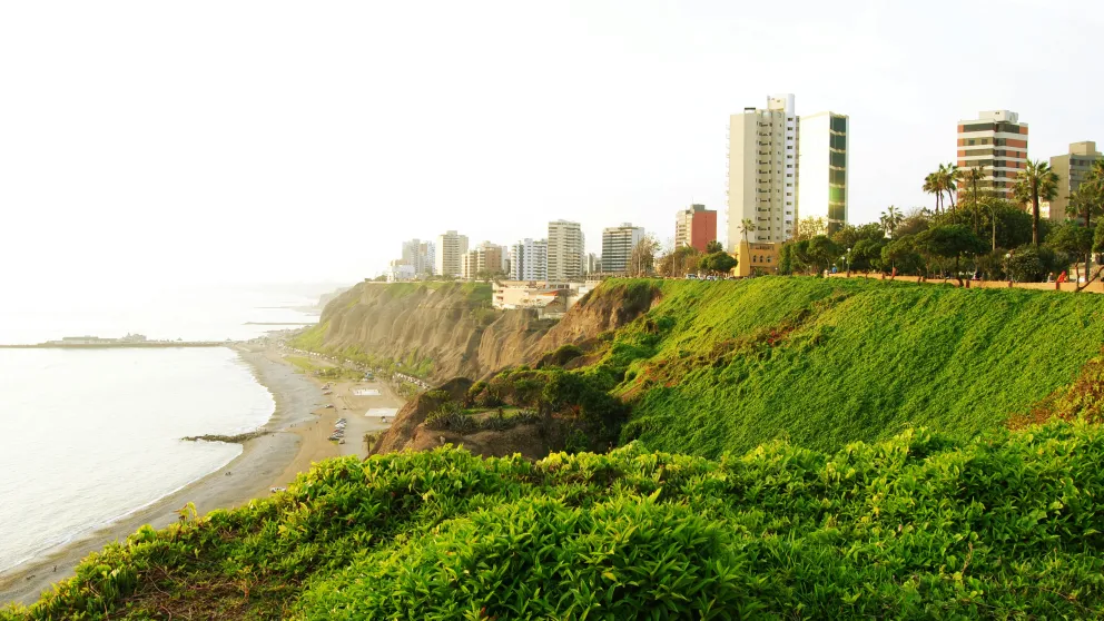 a oceanside view with green hills and city high-rise buildings