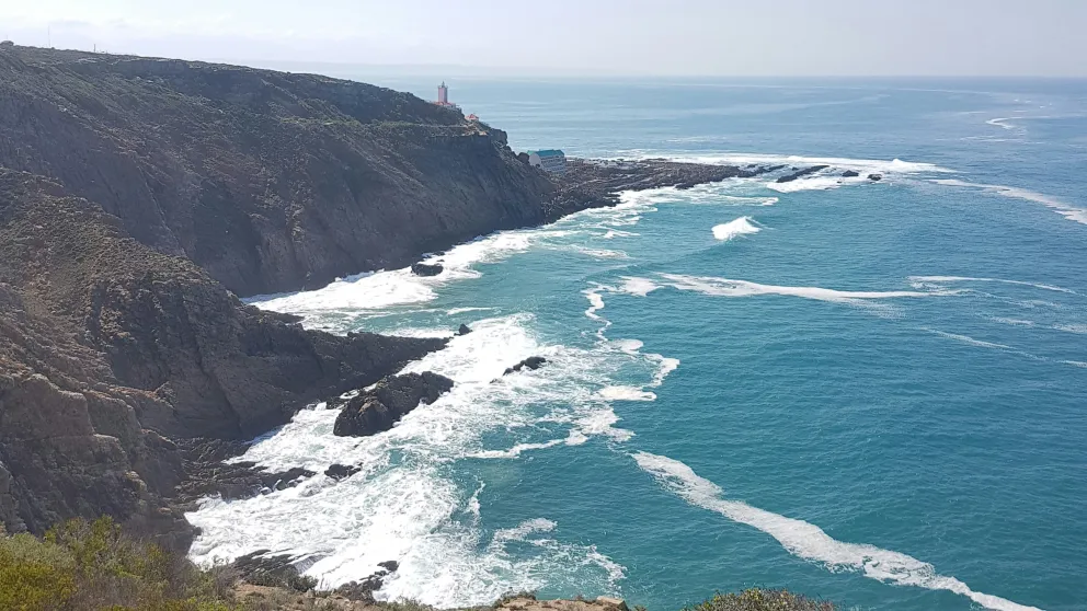 ocean waves crashing against a hilly shoreline