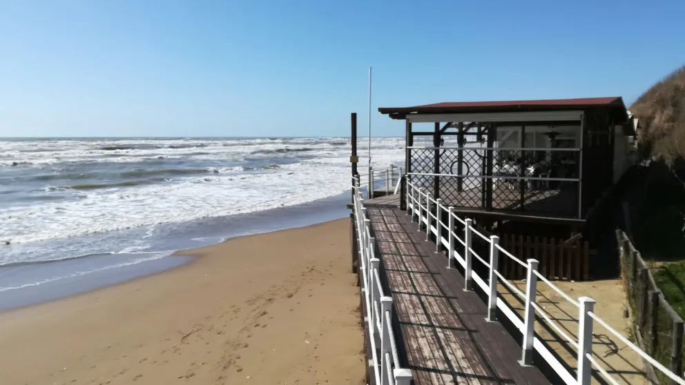 a small building and walkway on the beach overlooking the ocean