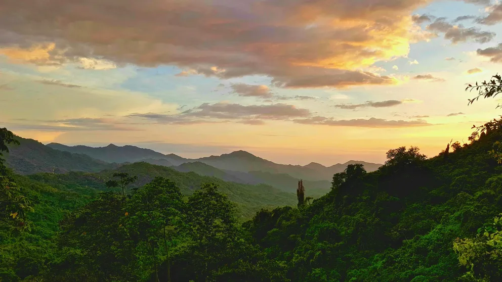 green hills with a cloudy sunset sky