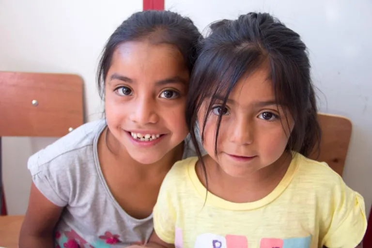 Two girls in school chairs at Eagle's Nest Orphanage