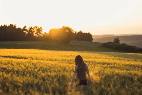A woman walking through a wheat field.