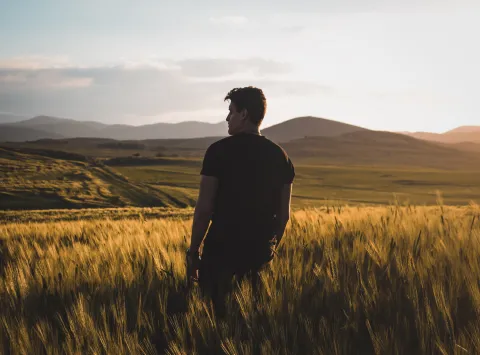 A young man standing in a wheat field.