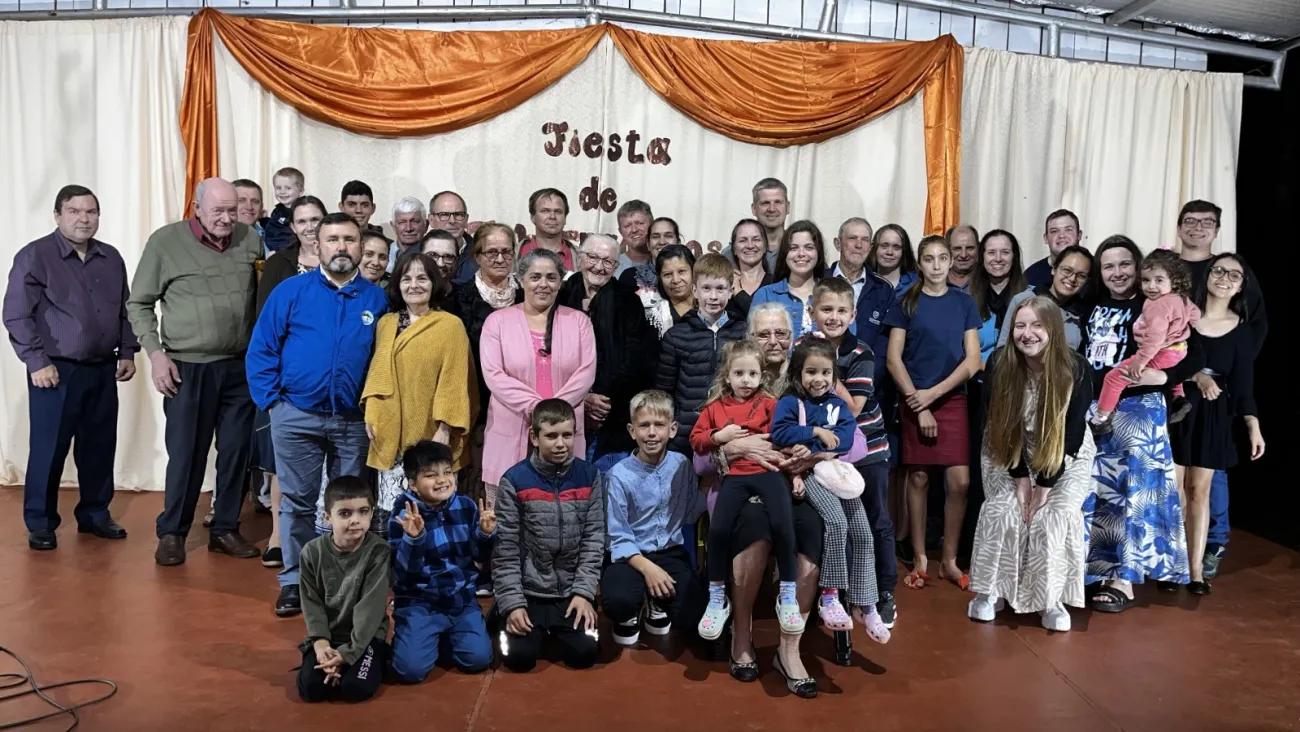 2024 Feast of Tabernacles Gobernador Roca, Argentina a group of people standing indoors in front of a curtain backdrop