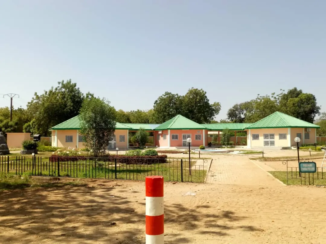 a building in a park with a dirt path leading to it
