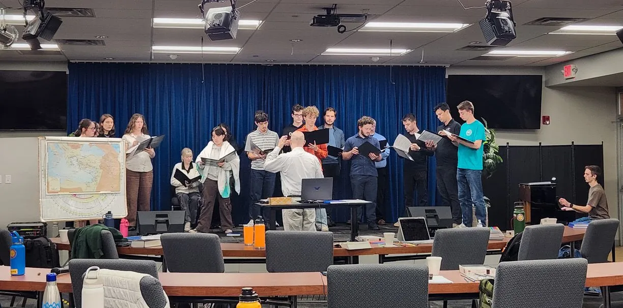 Group of young adults on a stage holding binders