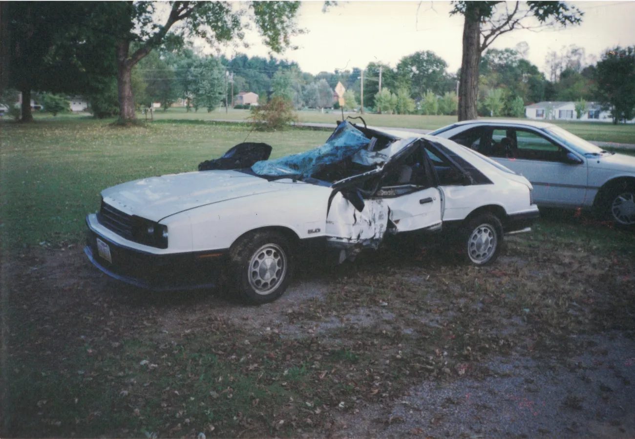 Exhibit B Totaled white car with roof collapsed in and glass shattered