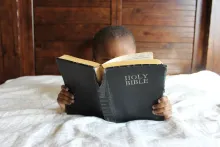 A little boy looking at a Bible.
