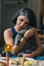 a sad woman hugging a gray cat