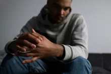 a sad man with folded hands