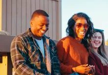 one man and two women seated outdoors in sunlight