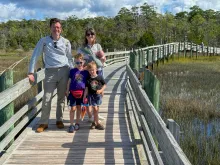 a man, woman, and two boys walking on a bridge