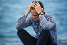 a man sitting and holding his head in his hands